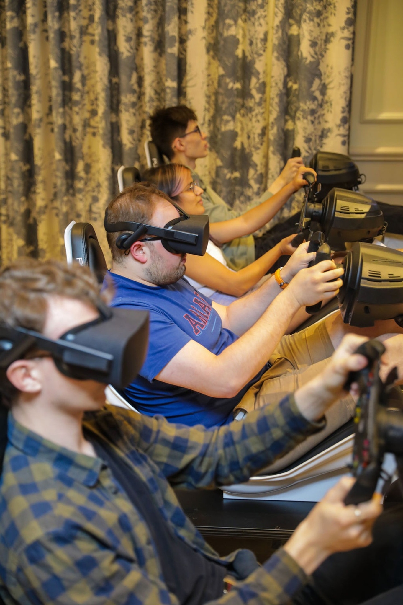 People on driving simulators with two people wearing VR heatsets